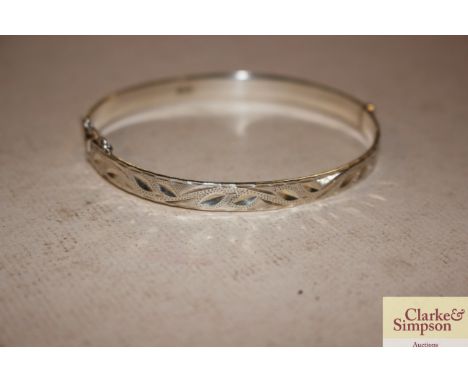 A silver hinged bangle with safety chain