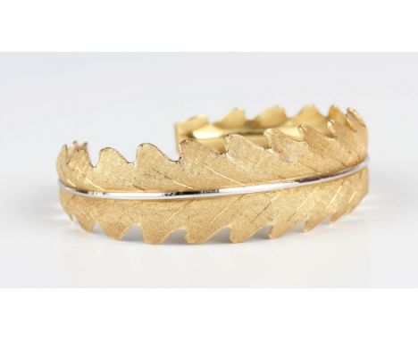 An Italian Buccellati two colour gold bangle of tapered leaf form, detailed '750', weight 20.7g, inside width 5.8cm, with a c