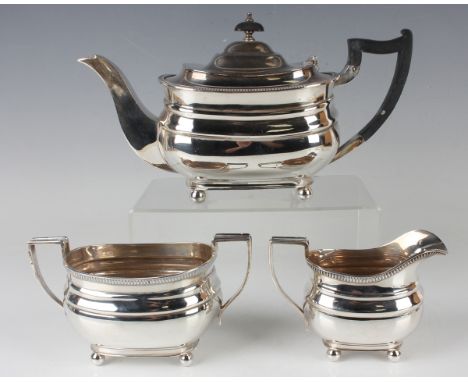 A George VI silver three-piece tea set of cushion form with gadrooned rims, raised on ball feet, comprising teapot, two-handl