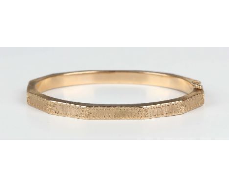 A 9ct gold faceted oval hinged bangle with engraved decoration, on a snap clasp, weight 11.3g, inside width 5.8cm.Buyer’s Pre