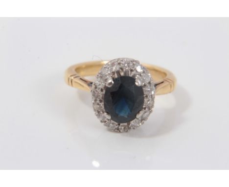 Gold (18ct) sapphire and diamond cluster ring with an oval mixed cut sapphire surrounded by a border of fifteen brilliant cut