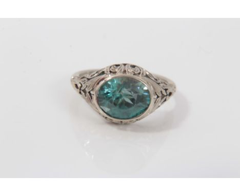 Blue zircon ring with an oval mixed cut blue zircon in scroll setting on white metal shank engraved Pat- Edie 1929. Ring size