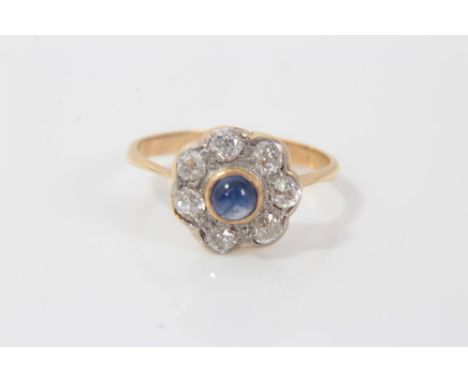 Edwardian sapphire and diamond cluster ring with a central blue sapphire cabochon surrounded by seven old cut diamonds on yel