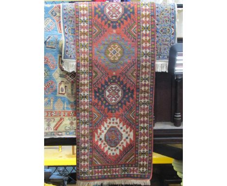 A wool runner in the Persian style, the multi medallion centre upon a brick red field within alternating borders, 290 x 80 cm