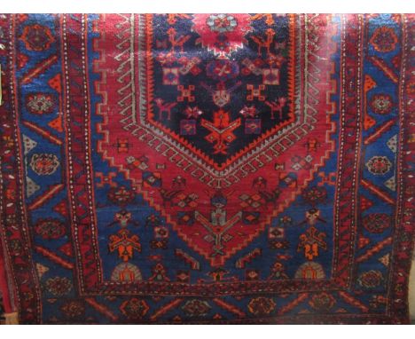 Persian wool runner, the central medallion in dark ink colour upon a red and blue alternating field within running borders wi