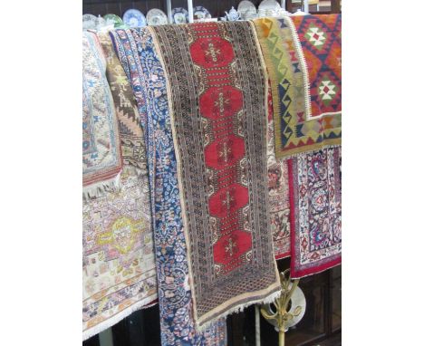 A red ground Persian wool runner with repeating geometric detail principally in a black and white colourway within several ru