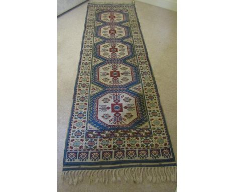 A Turkey wool runner with mid blue ground, several repeating hexagonal medallions within white running borders with further r