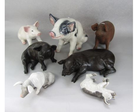 A collection of ceramic and other pig ornaments including a large model of a black and white seated pig, 31cm tall approx, a 