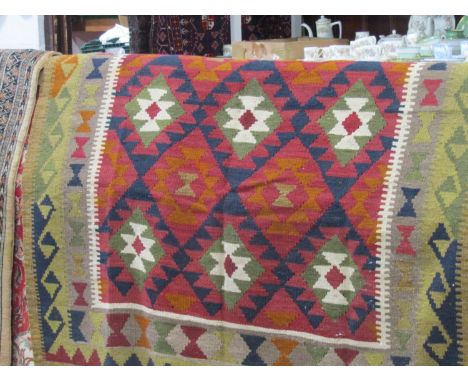 A Kelim carpet with multiple lozenge shaped medallions within a white dog tooth border and further alternating running border