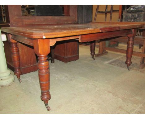 A Edwardian walnut wind out extending dining table of rectangular form with canted corners and moulded outline, two additiona