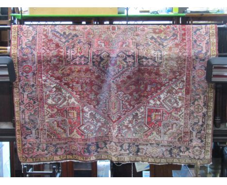 A Persian style wool carpet upon a general white field, principally in a red and yellow colourway within wide repeating borde