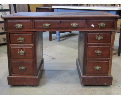 A late Victorian walnut kneehole twin pedestal writing desk with inset faux leather top over the usual arrangement of nine fr