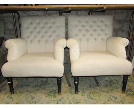 A pair of traditional button back armchairs in an oatmeal coloured fabric raised on turned and ebonised supports 