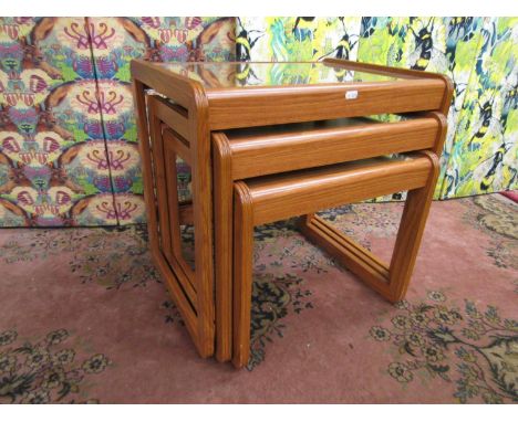 Nest of three light teak tables with glass tops and square framework, the largest 54cm wide x 52cm high (3) 