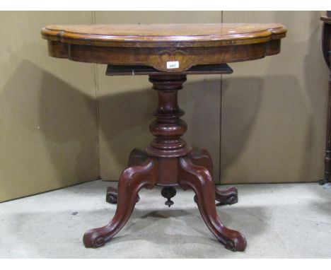 A Victorian walnut and figured walnut shaped D end fold over top card table raised on a turned pillar and quadruped base, the