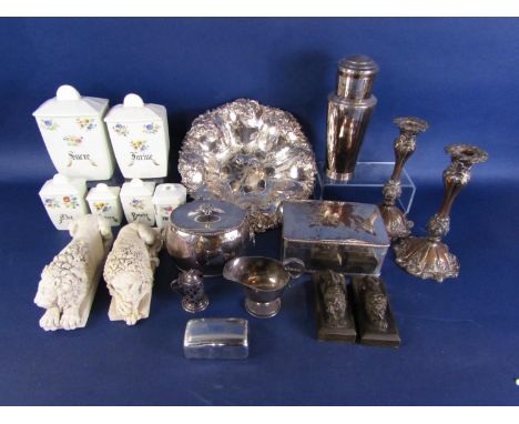 A collection of plated wares including a circular dish with embossed fruiting vine decoration, a pair of candlesticks, a cadd