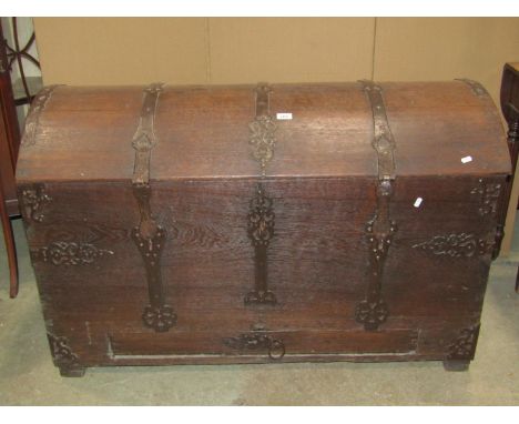 An 18th century oak domed top trunk/coffer with exposed strap work hinges, lasps and fittings and incorporating a shallow dra