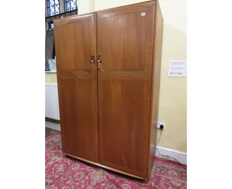 Ercol light elm two door wardrobe, the hinged doors enclosing an interior fitted with a clothes rail and four short drawers, 