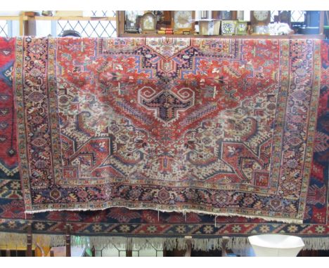 A large Persian wool carpet with red field and white ground outer borders and busy repeating running frieze, overall geometri