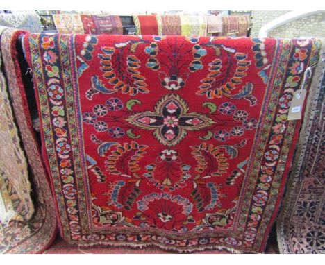 A red ground Persian style wool rug with abstract and floral detail within repeating borders 105 x 110 cm approx 