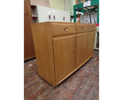Ercol light elm tall sideboard, fitted with three drawers over three cupboard doors, enclosing a shelved interior, 154cm long