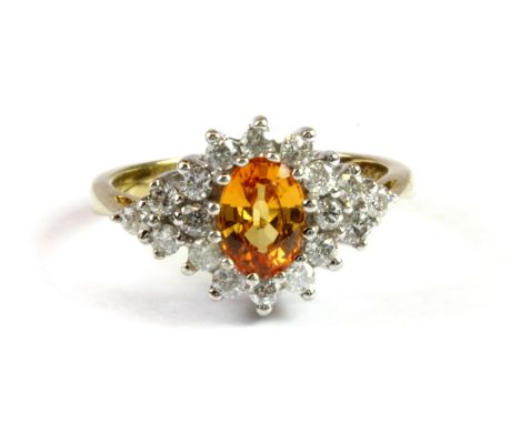 A 9ct yellow and white gold ring set with an oval cut orange sapphire surrounded by diamonds, (L.5).