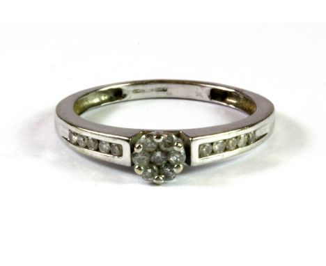 A 9ct white gold diamond set cluster ring with diamond set shoulders, (O).