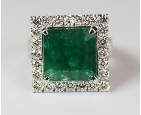 A superb 18ct white gold ring set with a large emerald (approx 10.10ct) surrounded by approx 2.3ct of brilliant cut diamonds.