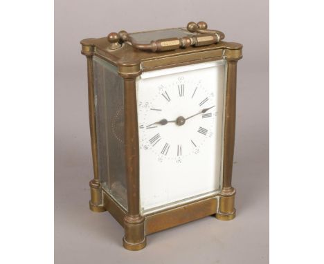 A brass and glass carriage clock with white enamel dial and glass top escapement.  Chips to glass.