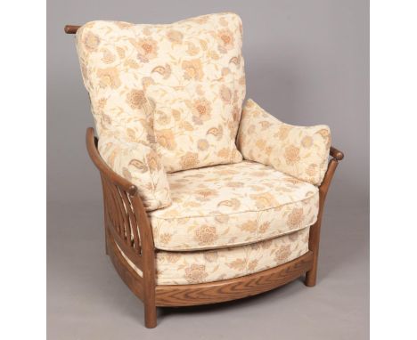 An Ercol 'New Renaissance' oversize low armchair in Golden Dawn finish, with light brown and cream floral upholstery.  