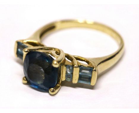 A 9ct gold. blue topaz and aquamarine ring, the claw set rounded square blue topaz approx. 9mm, each shoulder channel set two