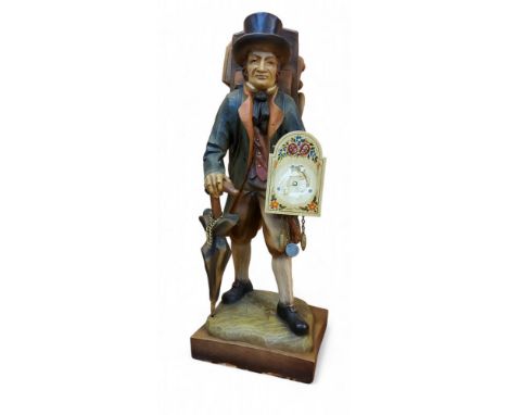 A 20th century carved and painted wood mantel timepiece, modelled as a travelling clockmaker carrying his wares on his back, 