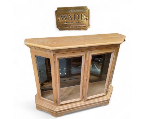 A Wade Furniture limed oak canted display cupboard, two doors opening to reveal a mirrored back and glass shelf, bracket feet