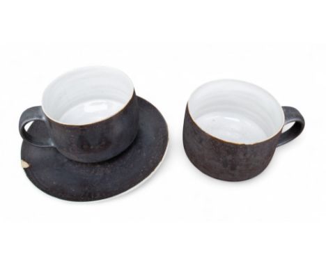 Dame Lucie Rie (British, 1902-1995) A cup and saucer, together with a further cup Stoneware with dark brown manganese glaze S