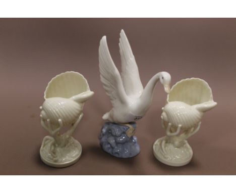 A NAO MODEL OF A SWAN TAKING FLIGHT + TWO BELLEEK STYLE CONCH SHELLS IN CORAL VASES  (3)