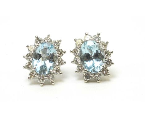 A pair of aquamarine and diamond cluster earrings, each principal oval facet-cut aquamarine measuring approximately 8.0 x 6.0