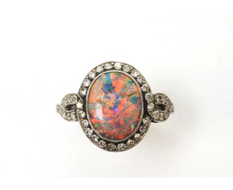 A black opal and diamond cluster ring, the oval black opal cabochon (cracked) 12 x 9.5 x 2.6mm, in collet millegrain setting 