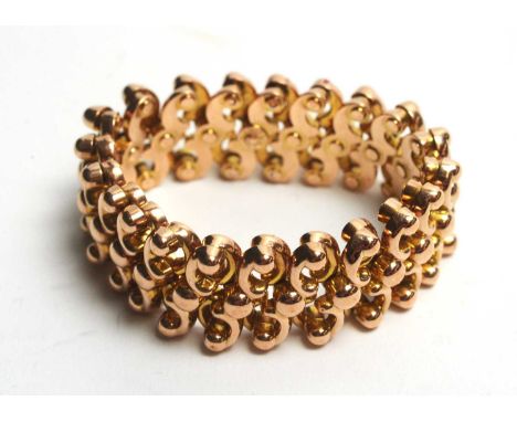 A Victorian yellow metal expanding bracelet, Baden patent, stamped '9', of scrolling riveted links, 11cms wide at largest, 15