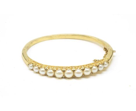 A pearl and diamond bangle, the eleven graduated half pearls measuring from 6.3-3.8mm diameter, surrounded by rose-cut diamon