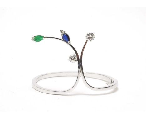 A diamond, sapphire and emerald set bangle, the stiff white metal bangle stamped '18k', of shaped form, set with four brillia