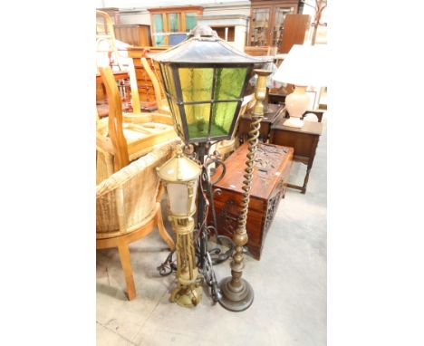 A floor standing wrought iron lantern, 133cm high, together with a brass example and a brass barley twist candlestick (3)