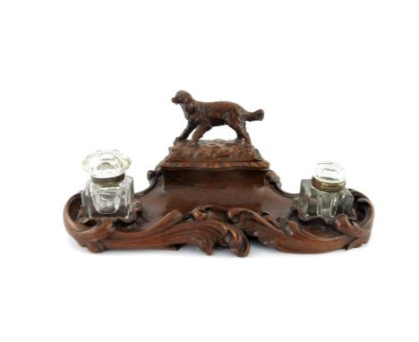 A late 19th Century Black Forest double desk inkwell, of serpentine form with high relief carved scroll border, writing requi