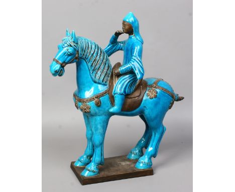 An Asian ceramic model of a figure on horseback decorated with turquoise glaze raised on a plinth.