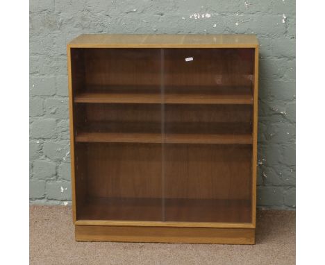 A light oak bookcase with smoked glass sliding doors.