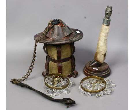 A taxidermy hoof base tablelamp along with a leather lantern and two bag chandeliers.