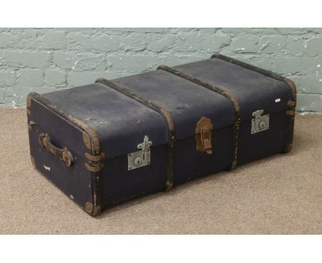 A blue wood bound leather travel trunk with leather handles.