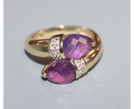 A modern 14k yellow metal and two stone amethyst crossover ring, size N/O.