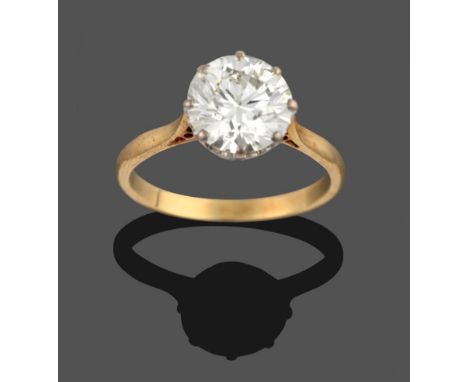 An 18 Carat Gold Diamond Solitaire Ring, the round brilliant cut diamond in a white claw setting to a yellow tapered shoulder