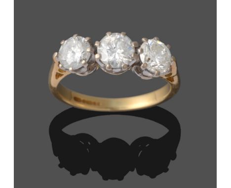 A Diamond Three Stone Ring, the round brilliant cut diamond in white claw settings on a yellow tapered shoulder shank, total 