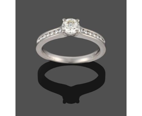 A Platinum Diamond Ring, the round brilliant cut diamond in a four claw setting, to shoulders inset with round brilliant cut 